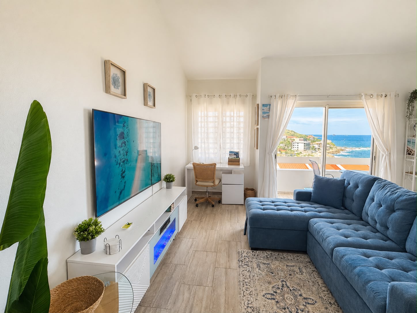 Living room with blue sectional and ocean view through the terrace doors