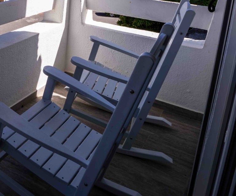 Two white rocking chairs on the shaded balcony