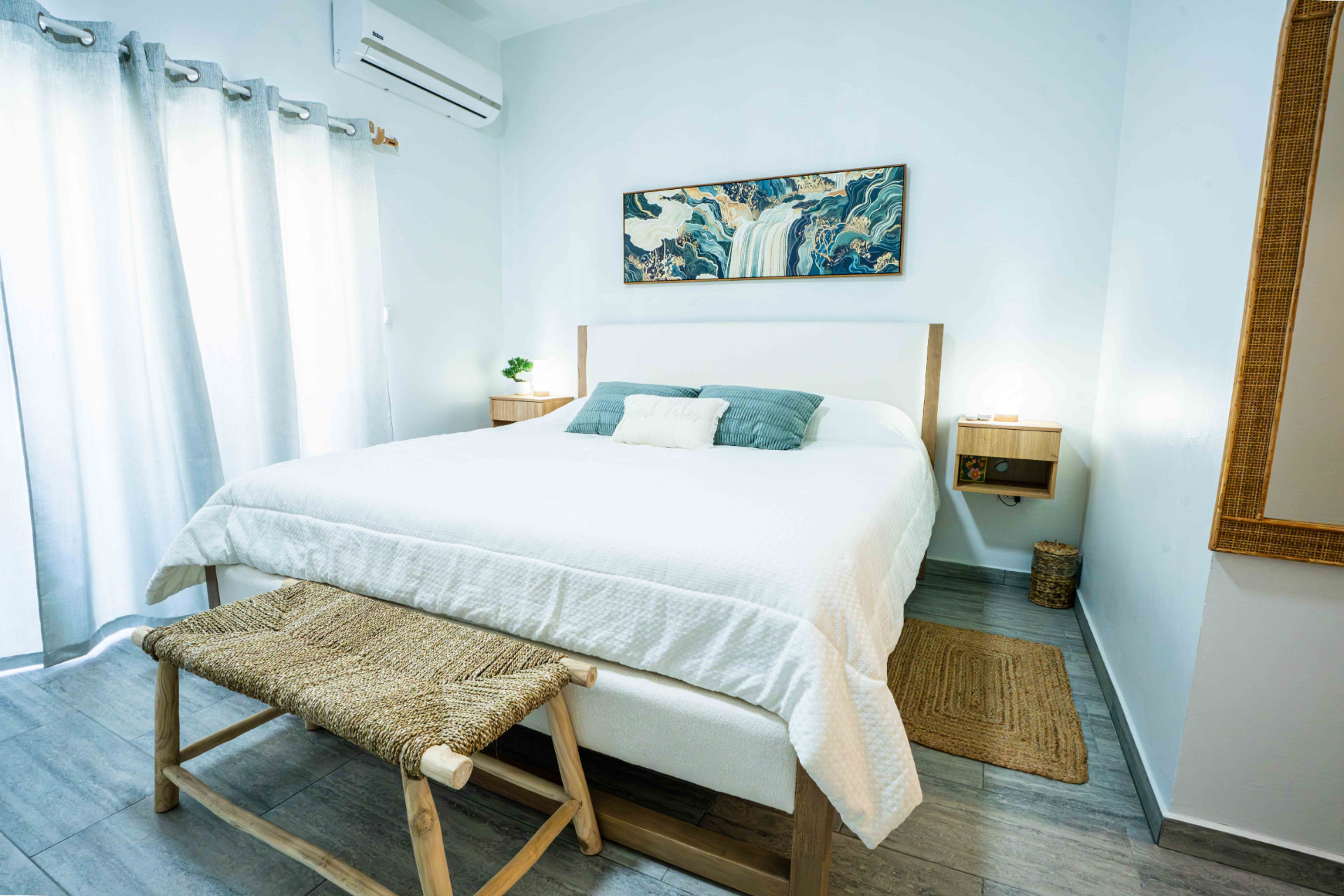 King bedroom with airy white linens and coastal artwork
