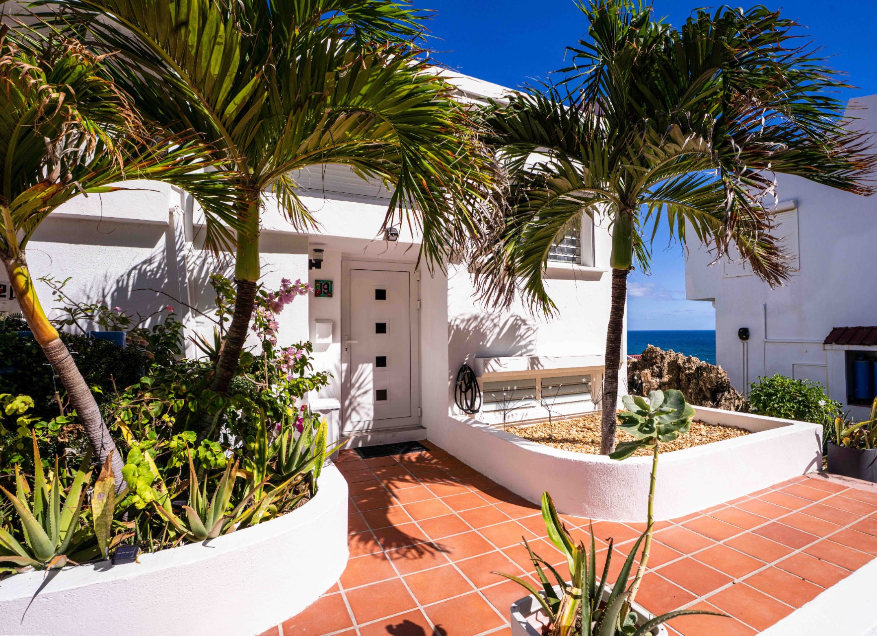 Private entrance framed by palms and tropical planting