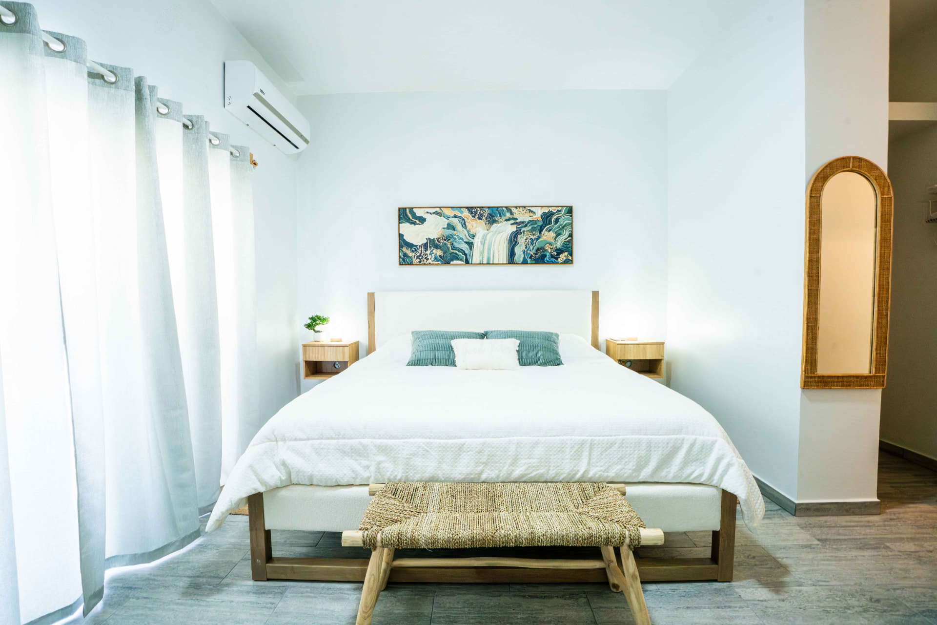 King bed with ocean inspired artwork and woven bench