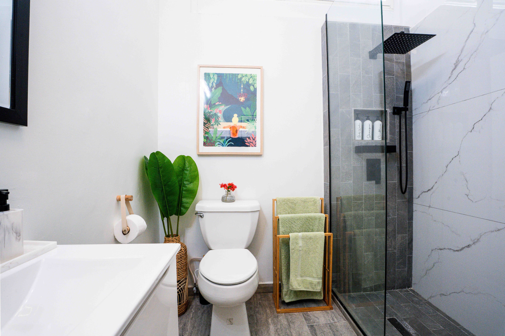 Bathroom with glass shower, towel rack and artwork
